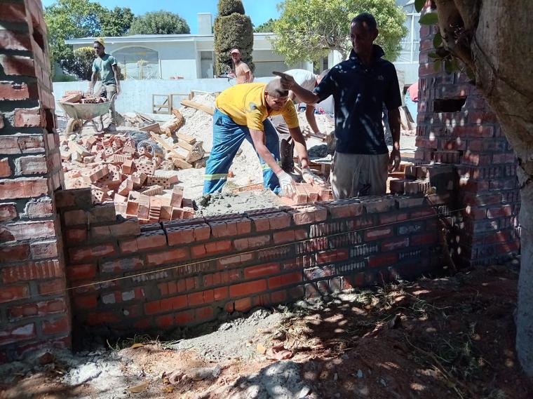 Bricklaying team building a garden wall to a string line