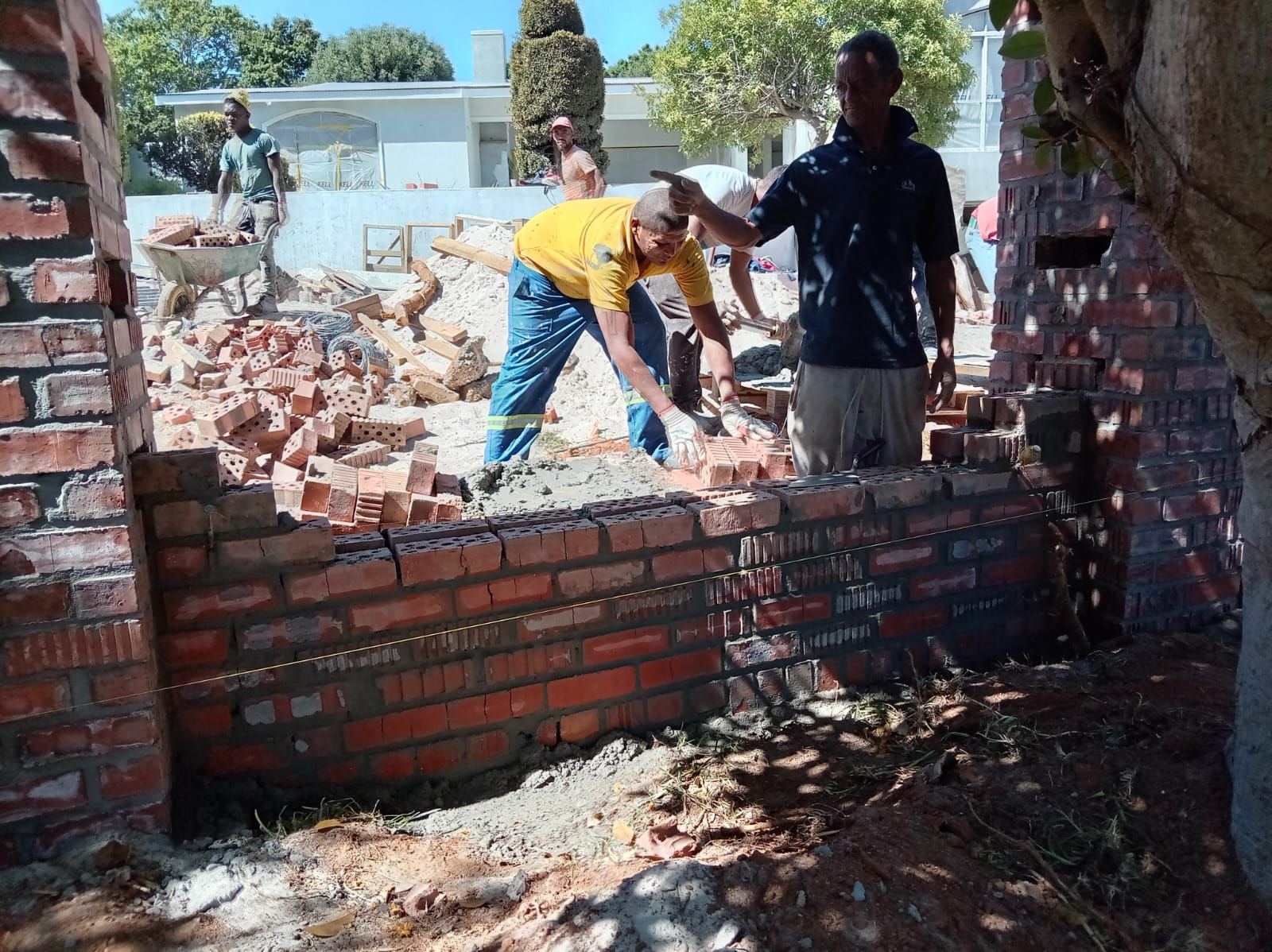 Bricklaying team building a garden boundary wall to a string line