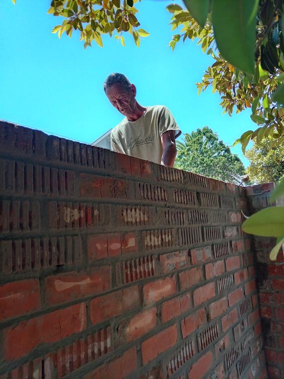 Bricklayer working along the top course of a face brick wall