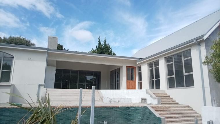 Finished white house with covered patio, steps and a tiled pool