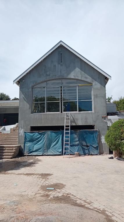 Plastered gable end with a large arched window opening and new roof edge