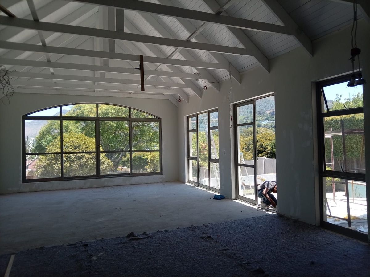 Interior of a new build with exposed white roof trusses and a large arched steel-framed window