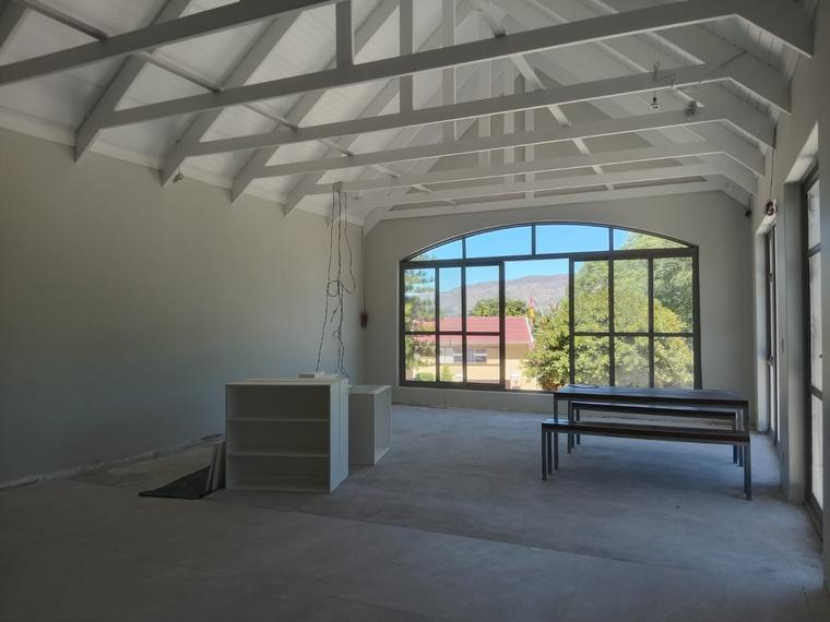 Open living space under exposed white trusses with an arched window to the mountain