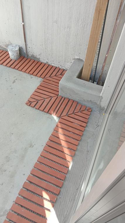 Clay brick paving set out in a herringbone pattern around a cast step