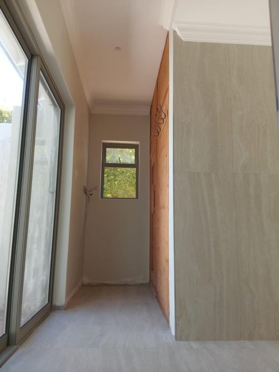 Hallway lined with large-format stone-look tiles beside timber panelling