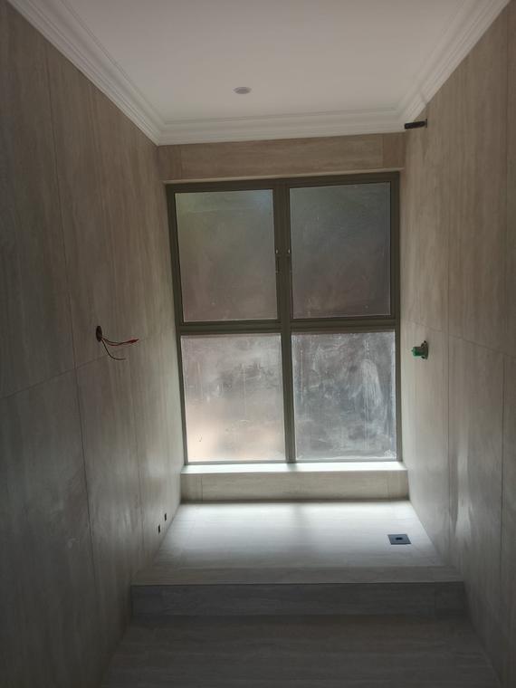 Window recess tiled floor to ceiling in large-format travertine-look tiles