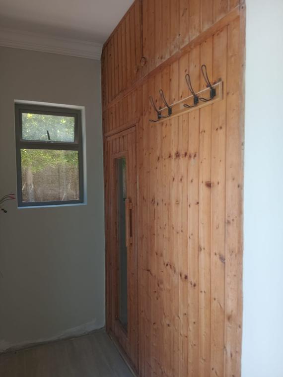 Pine tongue-and-groove panelled wall with a coat rail and glazed door