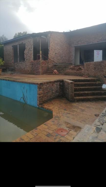 House stripped back to brickwork with roof and openings removed, pool in foreground